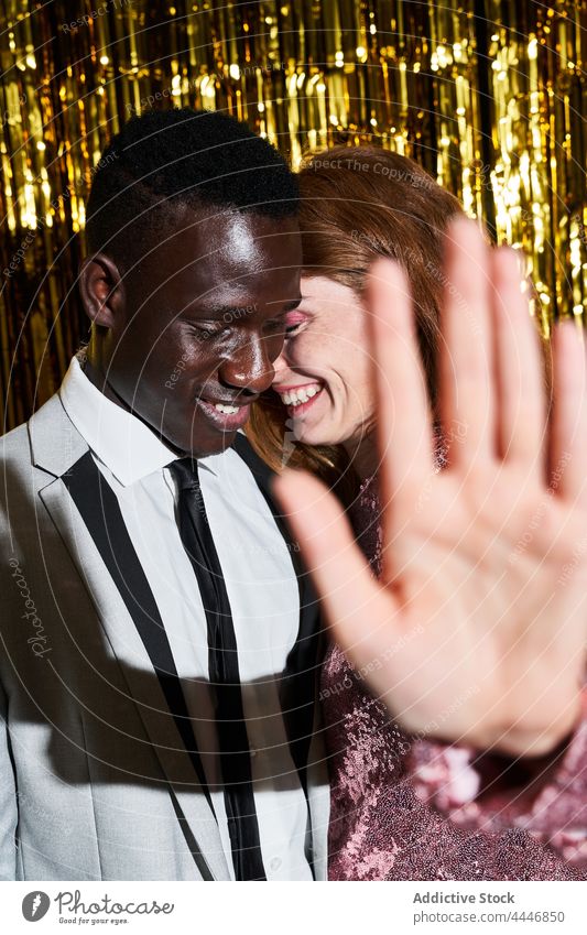 Smiling woman showing stop gesture against black boyfriend during party couple smile control relationship private new year eve hide celebrate style festive