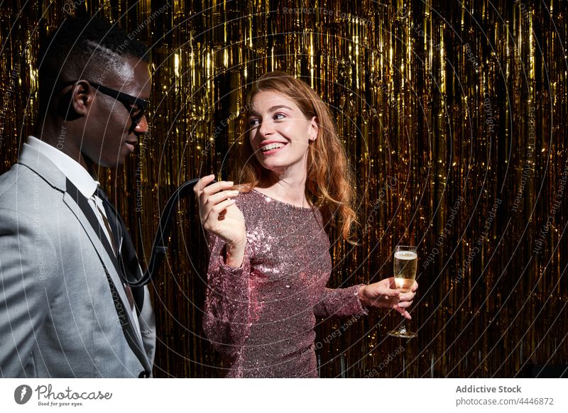 Stylish multiethnic couple with champagne talking during party relationship romantic new year celebrate interact holiday smile jacket love content style enjoy