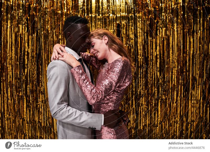 Loving diverse couple embracing against tinsel during festive event embrace amour relationship new year party celebrate romance pleasure love romantic style