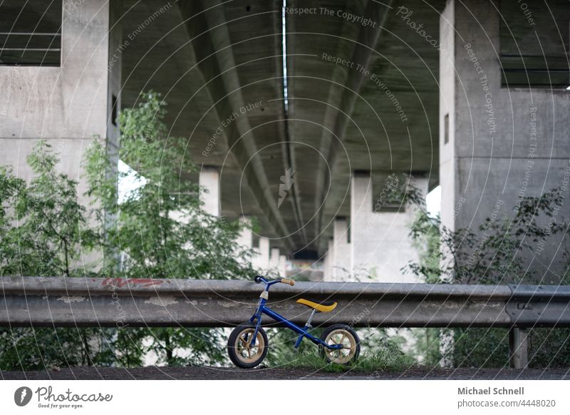 Old wheel on a guard rail under a motorway bridge impeller Child Infancy Exterior shot Movement Toddler Bicycle Playing Former Past Review Longing