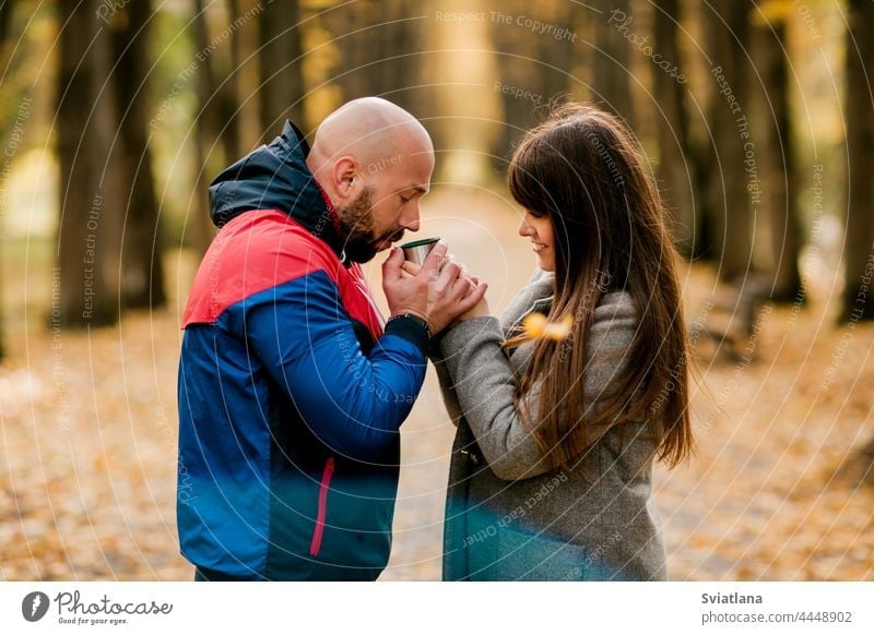 A married couple with a hot drink in the autumn park. The concept of love and relationships man woman tea thermos romantic nature happy coffee people female