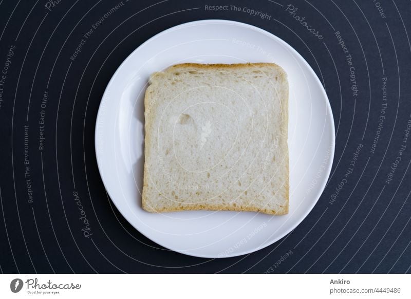A slice of toast on a white plate, black background bread top view sandwich isolated toasted food breakfast above snack sliced cut roasted fried textured