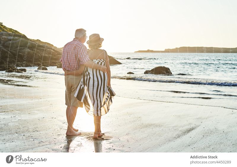 Anonymous senior couple standing on beach by waving sea sand love nature wife husband seacoast together relationship water bay shore summer barefoot summertime