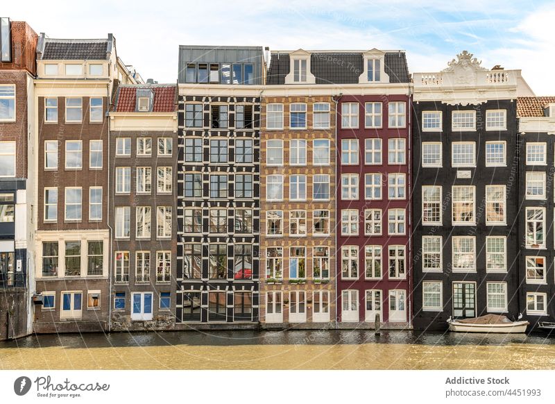 Multistory building facades against canal in sunny city architecture decor window reflection district multistory urban sky aged decoration row complex housing