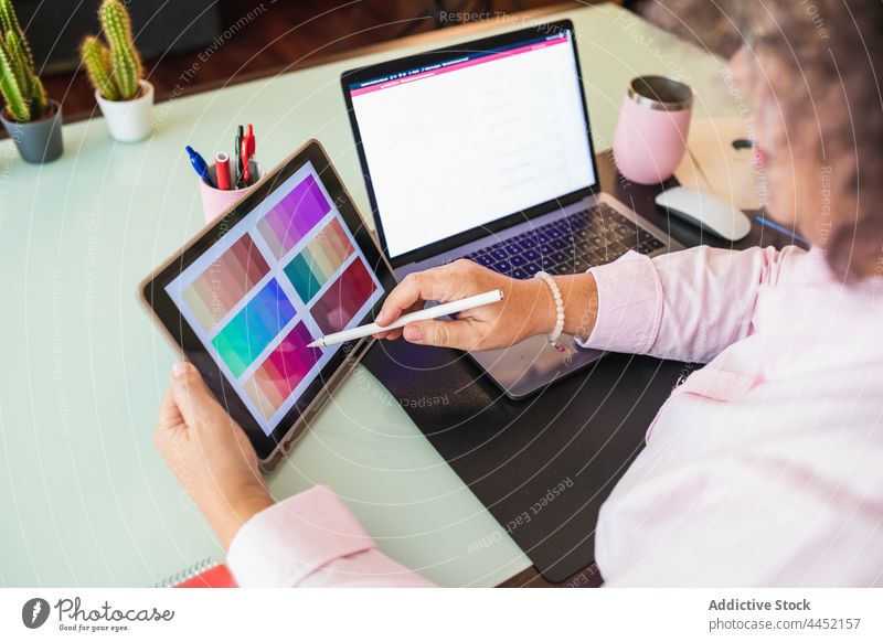 Crop businesswoman showing color palette on tablet during video call laptop senior explain touch screen office using gadget device multimedia netbook talk