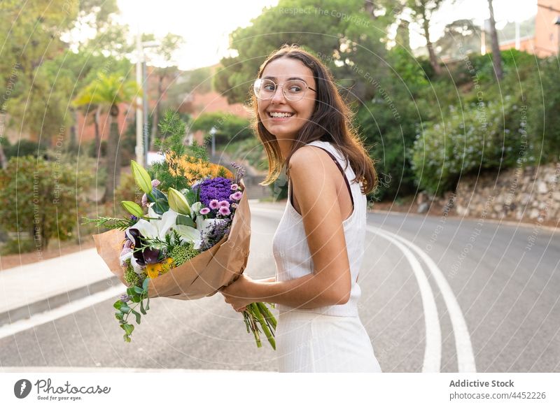 Happy woman with flower bouquet on urban road flora smile romantic friendly gift blossom surprise bloom cheerful sincere natural floral aroma content candid