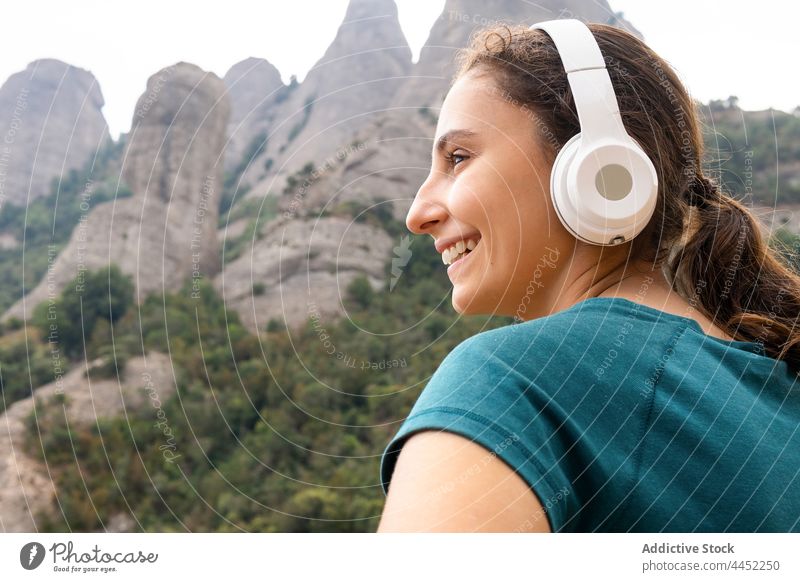 Mindful traveler listening to music from headphones against mountain song meloman woman using gadget device vacation dreamy enjoy tourist reflective nature tree