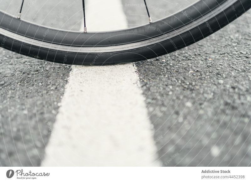 Bicycle wheel on asphalt road in daytime bicycle tire spoke rubber material geometry symmetry transport wavy roadway bike vehicle street marking line rough