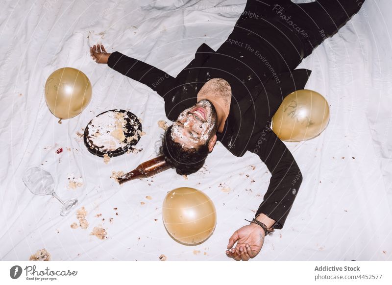 Happy man in smashed cake with eyes closed drunk laugh balloon booze birthday party messy male fun beer cheerful smile bottle celebrate happy event holiday