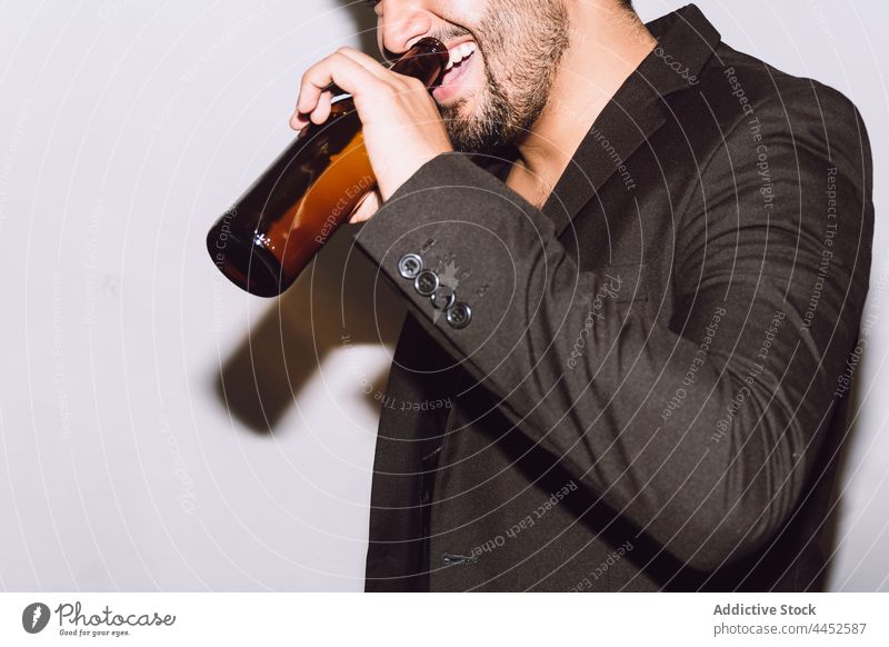 Happy bearded man drinking beer on face from bottle celebrate party booze enjoy holiday fun occasion male glass alcohol cheerful event festive glad content