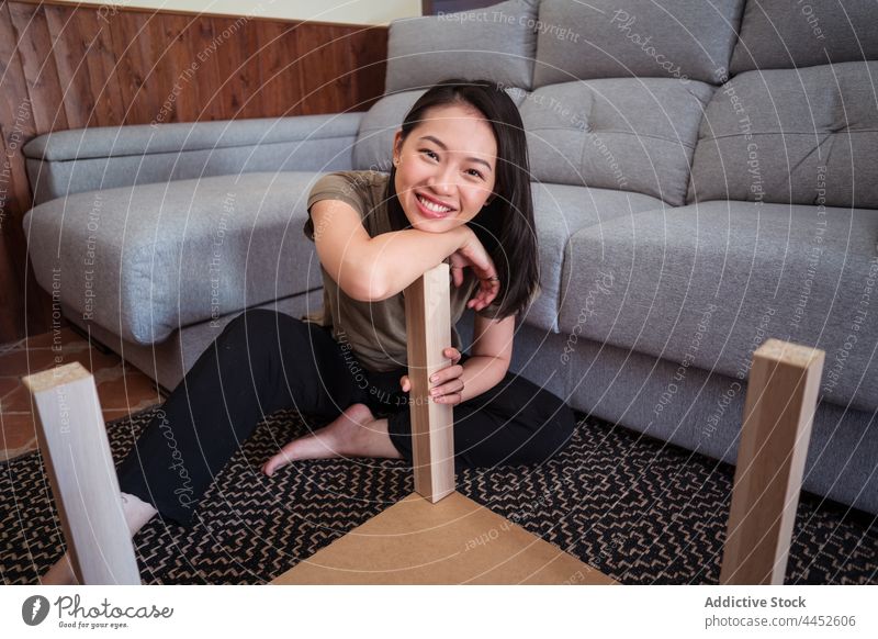 Asian woman assembling table in living room assemble attentive detail diy carpet ornament sofa home focus material barefoot concentrate couch sit rug floor