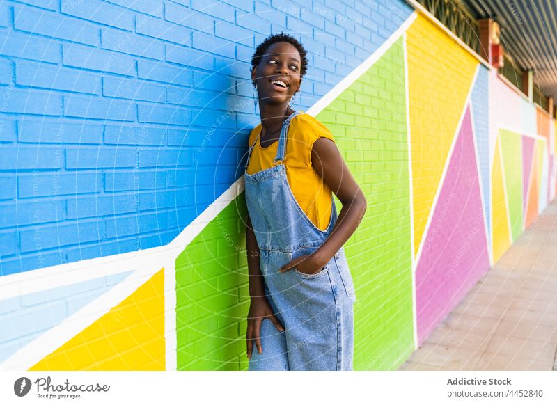 Energetic black woman standing against colorful wall positive action happy energy move female fun optimist glad casual carefree delight pleasure vivid playful