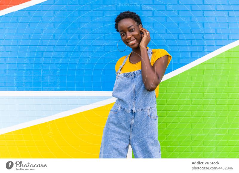 Energetic black woman standing against colorful wall positive action happy energy move female fun optimist glad casual carefree delight pleasure vivid playful
