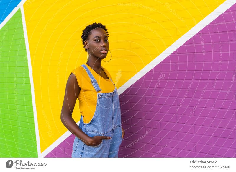 Black woman standing against colorful wall positive female fun optimist casual carefree pleasure vivid playful brunette ethnic african american black overall