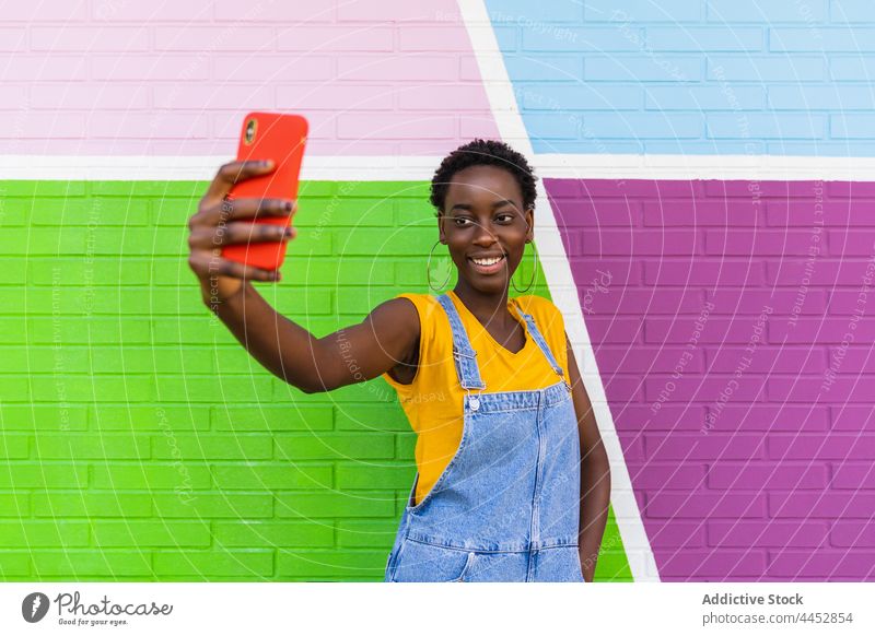 Smiling black woman taking selfie on smartphone using glad enjoy colorful capture photo screen female device happy self portrait delight digital cellphone
