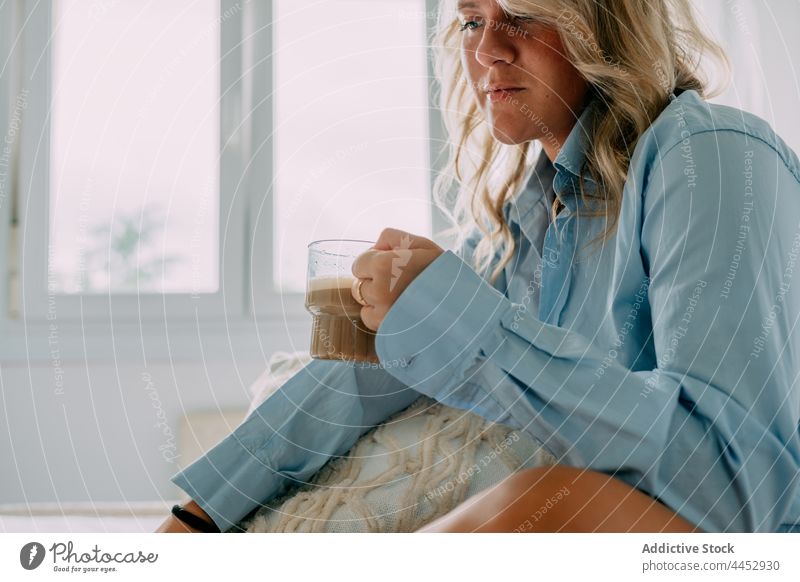 Crop woman with latte resting in house room coffee reflective wistful pensive hot drink beverage lonely home shirt cushion decorative natural aroma foam