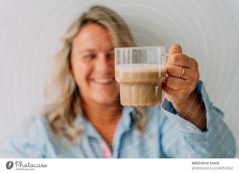 Cheerful woman with cup of aromatic latte coffee hot drink beverage foam natural cheerful pleasant scent dairy froth milk transparent ribbed smile content enjoy