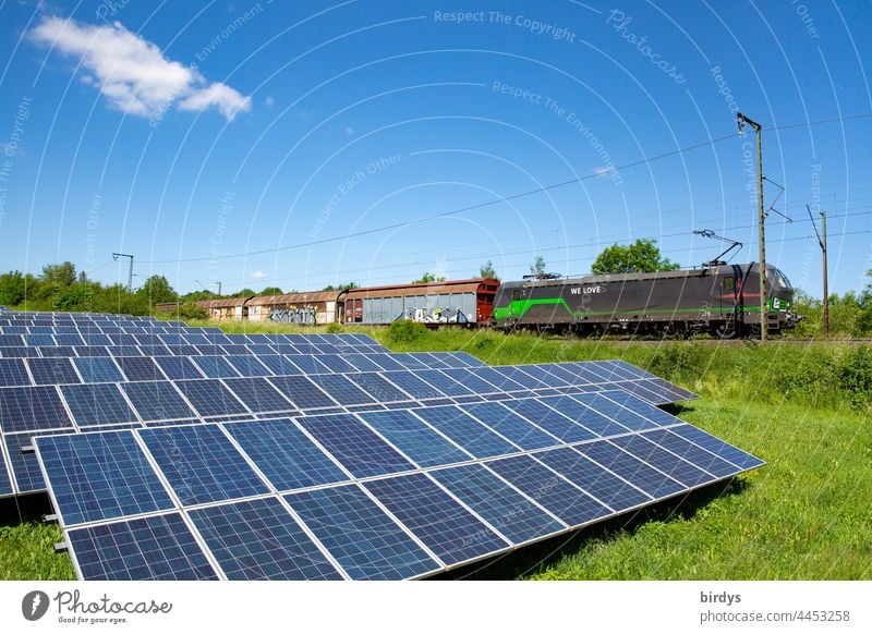 Open land - photovoltaic system next to a railway line with passing freight train Sustainability photovoltaics Ground-mounted photovoltaic system