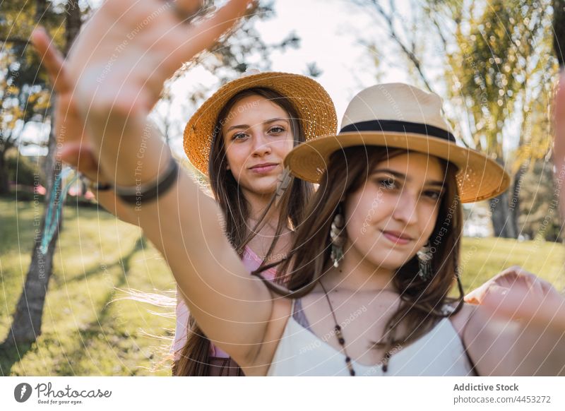 Smiling girlfriends in straw hats spending time in park smile friendship spend time weekend outstretch sincere millennial portrait teen best friend interact