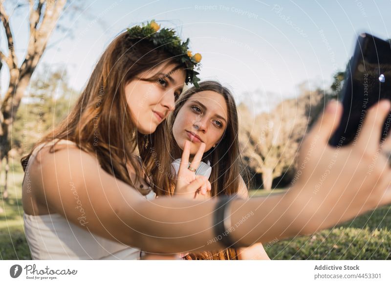 Girlfriends showing peace gesture while taking selfie on smartphone girlfriend two fingers memory moment spend time park using gadget device self portrait