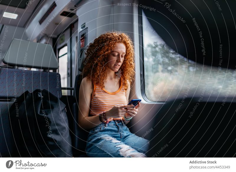 Passenger chatting on smartphone against window on train passenger internet online interested commute woman using gadget watching device text messaging surfing