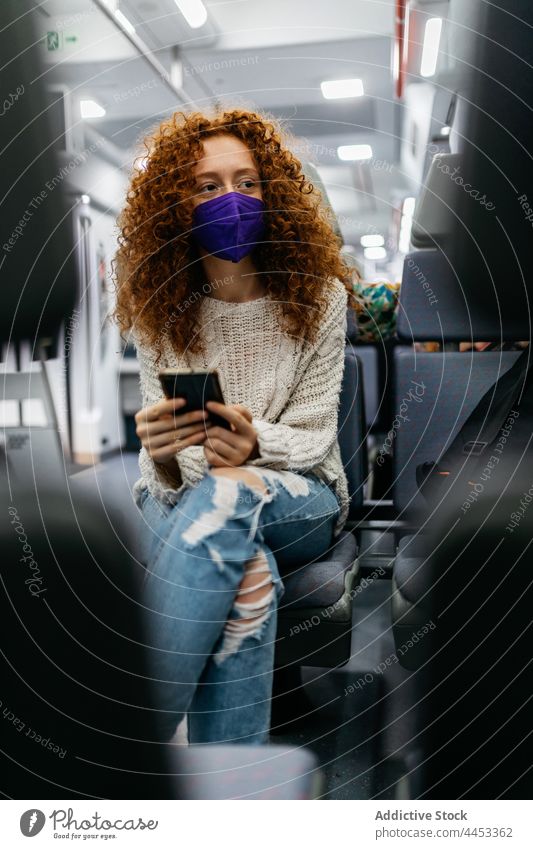 Passenger in textile mask chatting on smartphone on train passenger surfing internet new normal health care woman using gadget browsing attentive text messaging