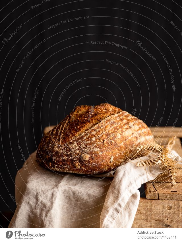 Sourdough wheat bread on towel on dark background sourdough artisan crust fresh tasty aroma baked whole cereal delicious spike creased organic fabric natural