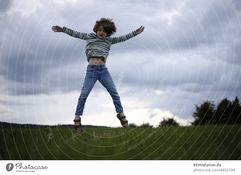 Child jumps on a meadow Infancy Boy (child) Athletic Jump Tall Dynamic Movement active Sports trees Joy Hop Exterior shot Leisure and hobbies Day Nature