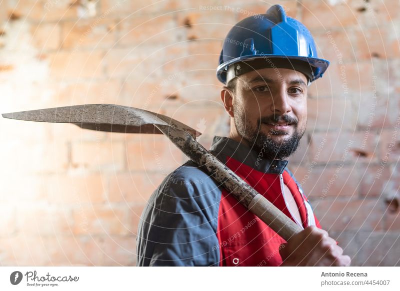 construction worker with shovel looks at camera with helmet smiling man bricklayer job arab 40s persona 35-39 years goatee indoor reforms renovations workplace