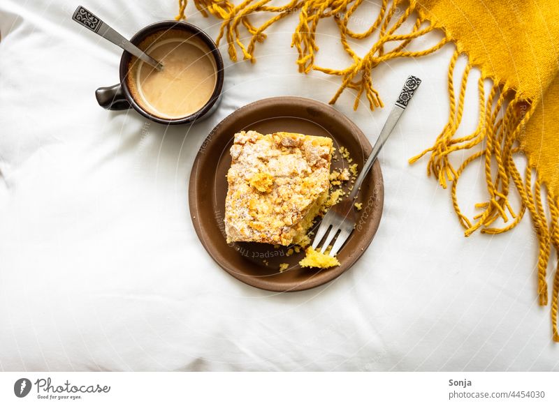 A piece of apple pie on a plate and a cup of coffee on a white bedspread. View from above. Breakfast Apple pie Coffee Coffee break Morning hygge Caffeine