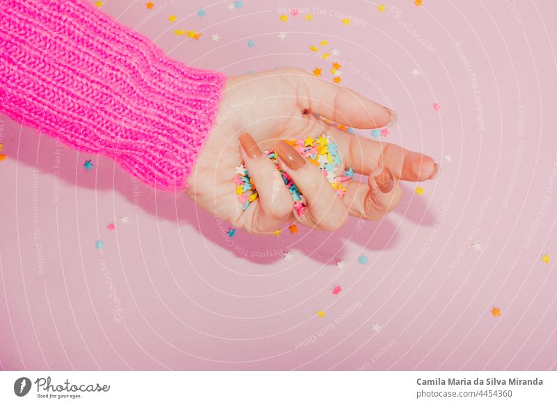 Top view of womans hands covered with colorful star confetti on light pink background. Christmas and celebration concept. beauty birthday carnival christmas