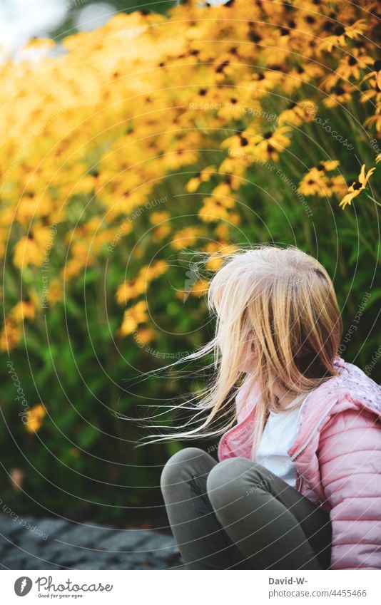 Wind blows through the hair of a young girl in front of a field of flowers Girl Blow Child Yellow Cute Blonde out naturally Infancy