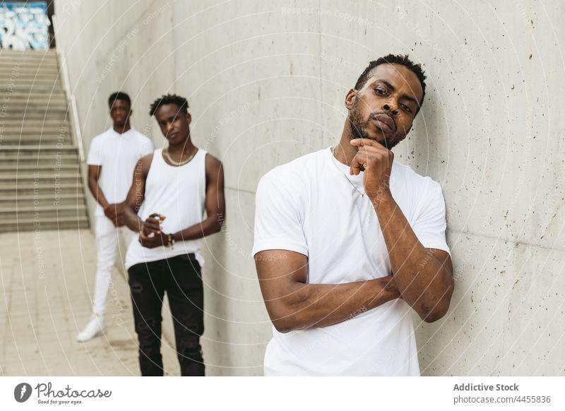 Black male friends in stylish outfits standing near concrete wall men cool style masculine trendy modern confident thoughtful individuality posture appearance