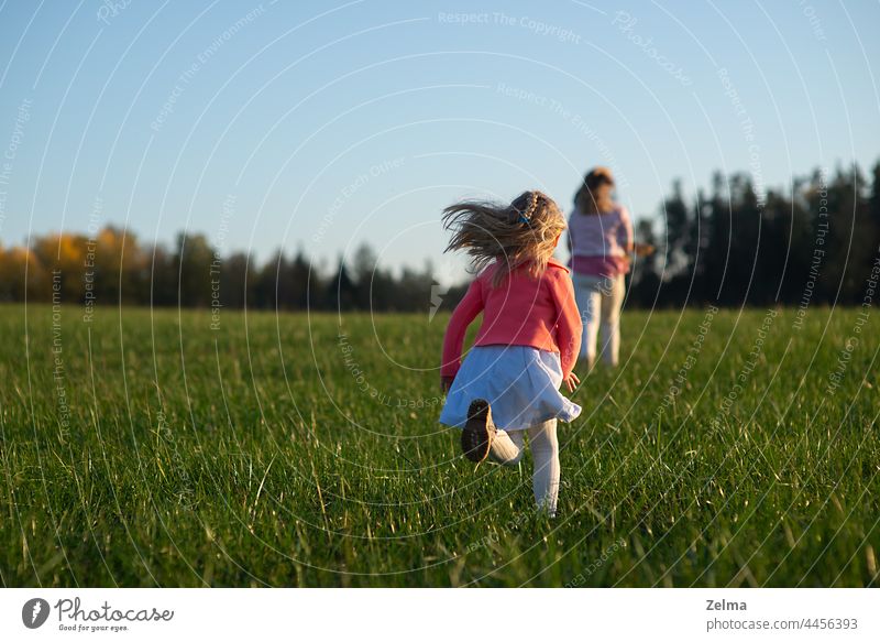 rear view on little girl child runs behind mom kid mother parent field meadow outdoors running Copy Space left people single mother Relationship family