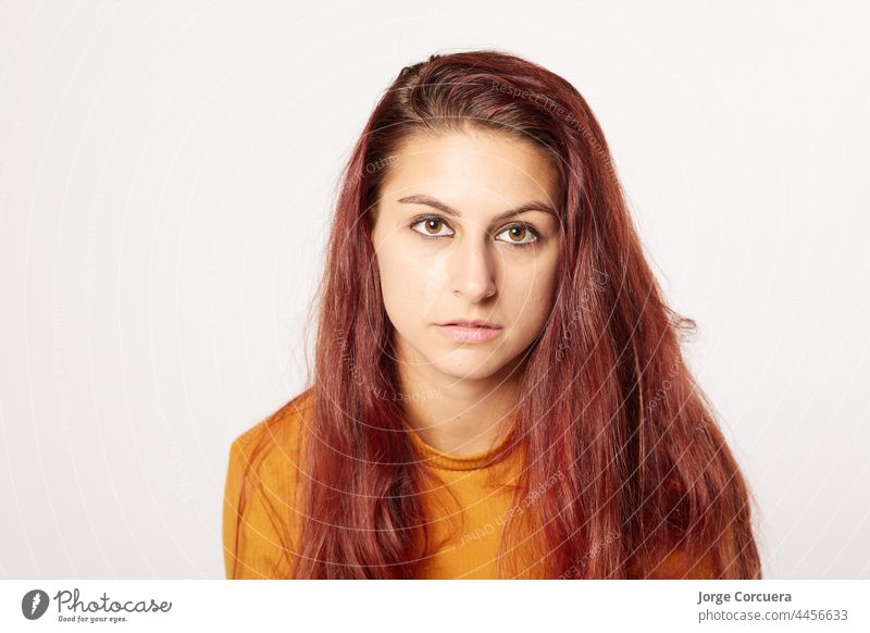 beautiful girl of 20 looking intensely at the camera with a neutral expression. Nice red hairstyle and orange sweater skin teenage optimist woman positive young