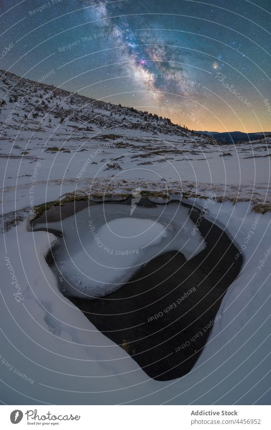 Snowy puddle of ice water under night starry sky with Milky Way snow mountain highland nature winter landscape terrain dirty ridge valley cold hillside frozen