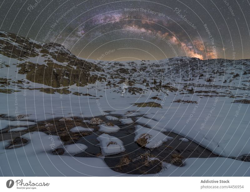 Snowy puddle of ice water under night starry sky with Milky Way snow mountain highland nature winter landscape terrain dirty ridge valley cold hillside frozen