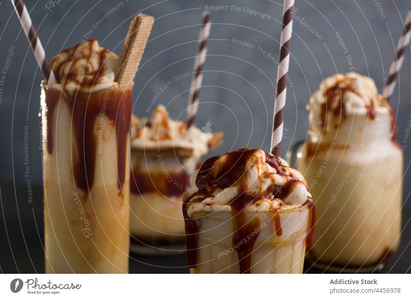 Tasty caramel milkshakes in glasses on table assorted serve wafer cookie sweet ice cream vanilla delicious drink straw tasty treat cold yummy dairy refreshment