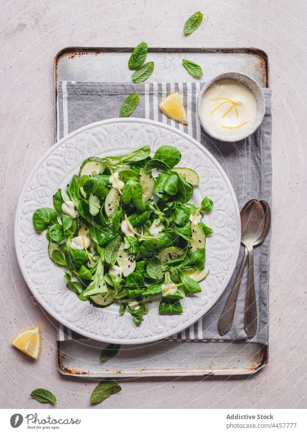 Mint and spinach salad against lemon sauce on gray background mint cucumber healthy food vitamin vegetable lunch portion delicious sesame seed zest citrus fruit