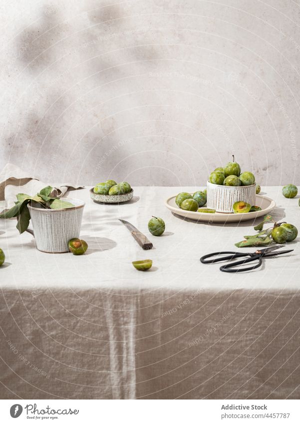 Green plums arranged on table still life green rustic creative tableware fresh ripe plate bowl healthy composition food organic tablecloth natural ingredient