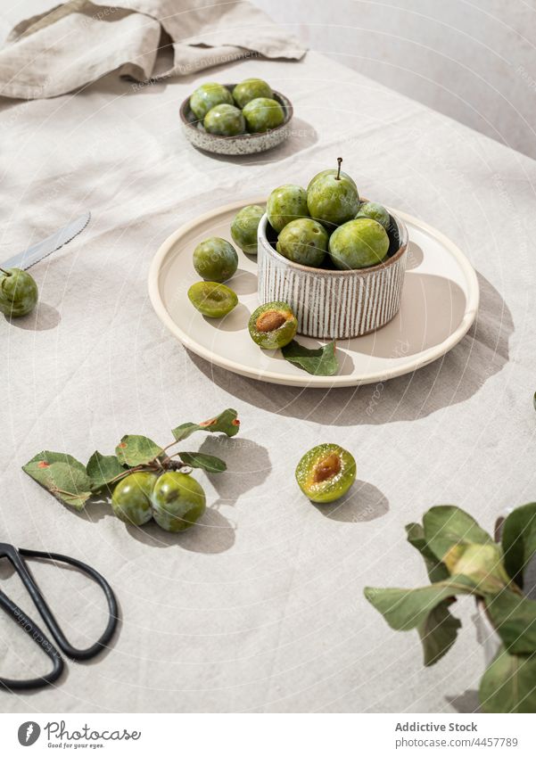 Green plums arranged on table still life green rustic creative tableware fresh ripe plate bowl healthy composition food organic tablecloth natural ingredient