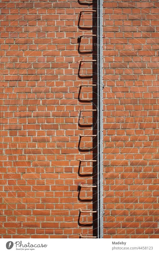 Old ladder for the chimney sweep in red-brown brick facade in summer sunshine in the Klassikstadt in the district of Fechenheim in Frankfurt am Main in Hesse