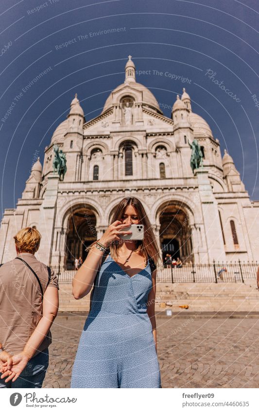 Woman taking photographs with a smartphone in front of Sacre Coeur basilica photographing camera woman walking street tourist travel tourism copy space Backpack