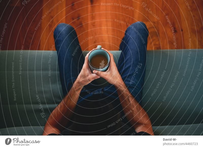 Coffee break - man holding a cup of coffee in his hands and sitting on the sofa Break stop tranquillity To enjoy Sit Sofa Cup Mug Coffee cup Man
