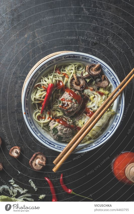 Tasty Asian food bowl with ramen noodles, meat balls, spices and chopsticks on dark background. Top view tasty asian food top view cooking dish traditional miso
