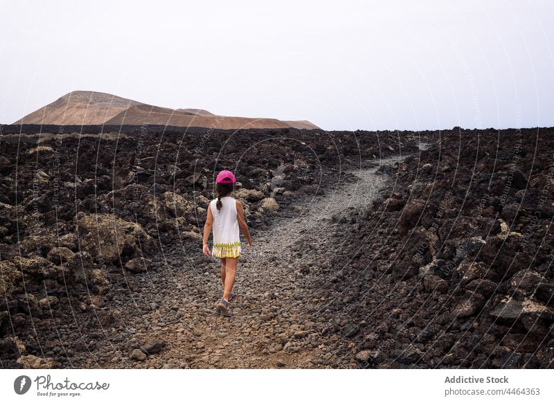 Little girl walking on path between lava child volcano nature explore sky highland pathway caldereta landscape geology barren island dry route direction
