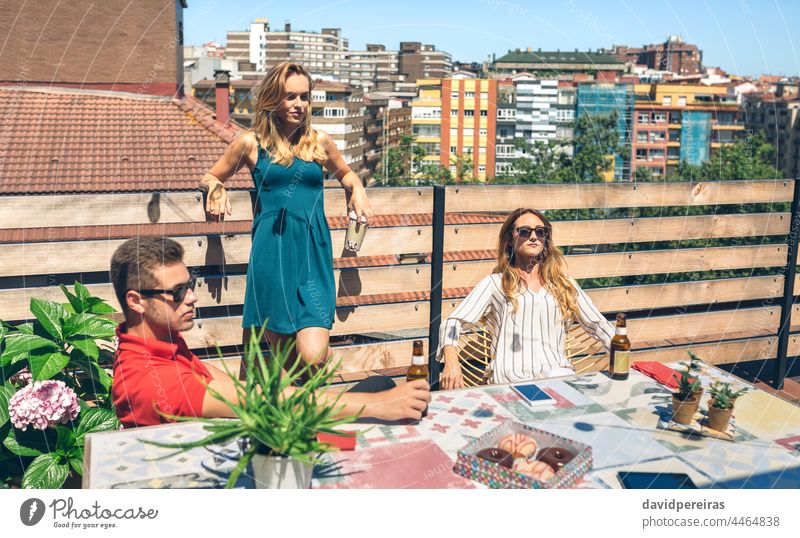 Friends drinking on a terrace group friends sunbathing beer young copy space rooftop serious elegant coffee bottle people female caucasian summer outdoor adult