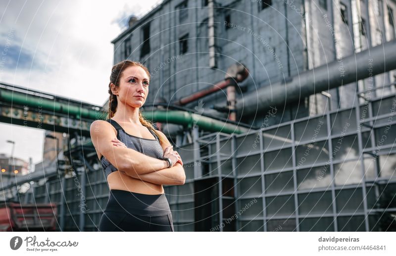 Sportswoman with crossed arms posing in front of a factory sportswoman industrial zone sporty copy space runner attractive jogger serious boxer braids adult