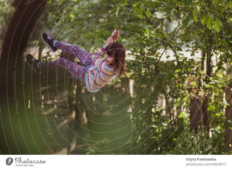 Happy girl on a tree swing in the garden action laugh cheerful outside playground leisure playful motion joyful freedom day excitement flying people lifestyle
