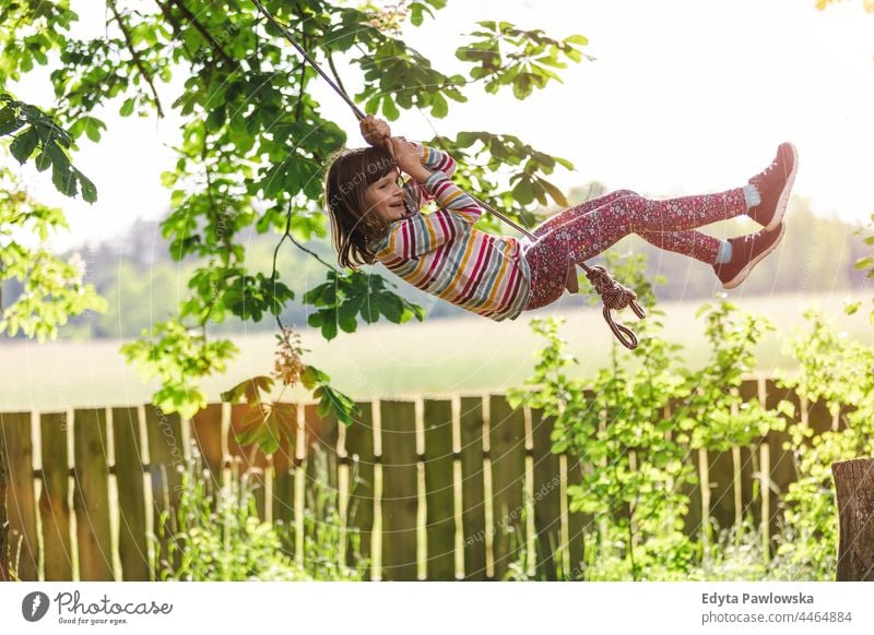 Happy girl on a tree swing in the garden action laugh cheerful outside playground leisure playful motion joyful freedom day excitement flying people lifestyle